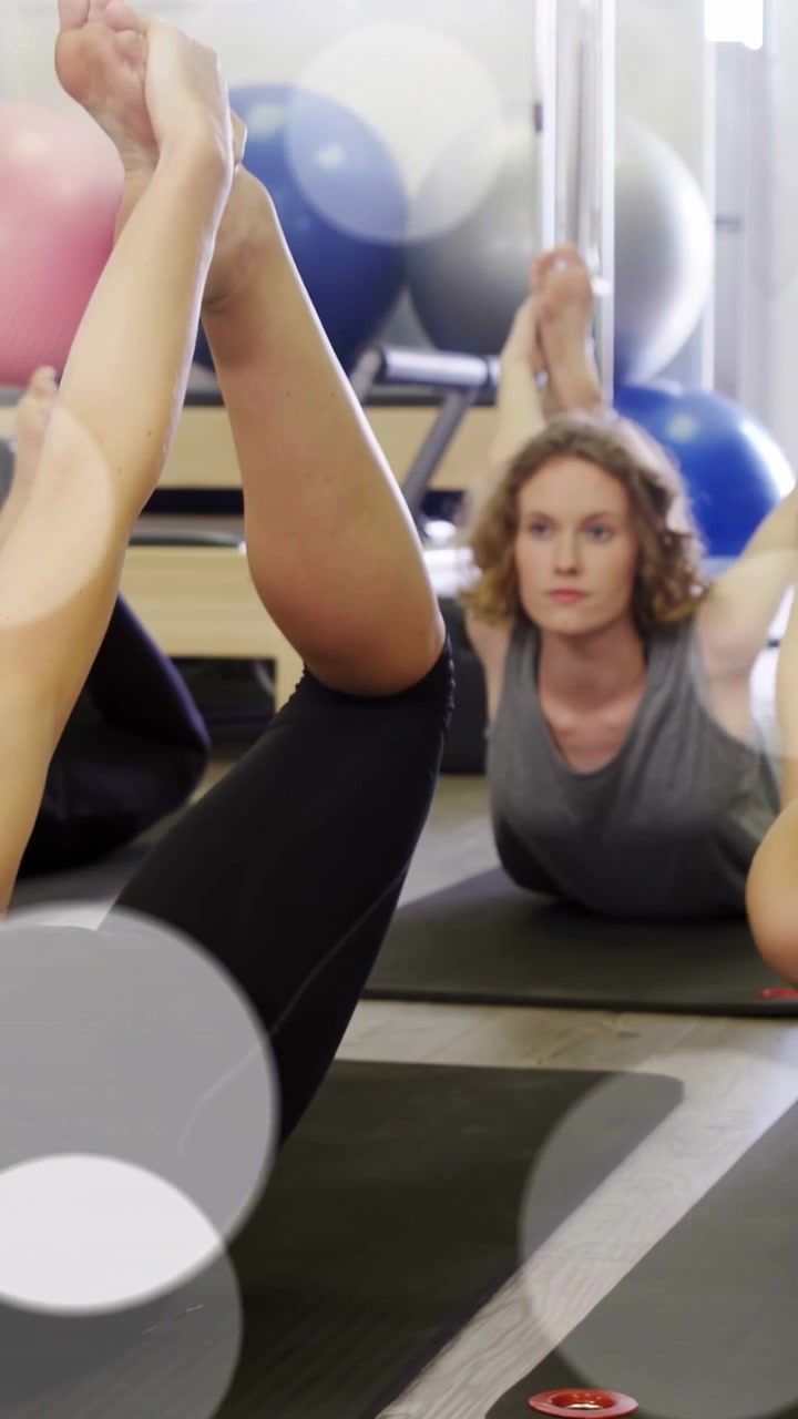 Video verticale: Donna che esegue un inchino su un tappetino nero, con la telecamera che si alza per una lezione di pilates guidata.
