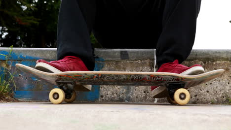 Young-skateboarder-sitting-at-the-outdoor-skatepark