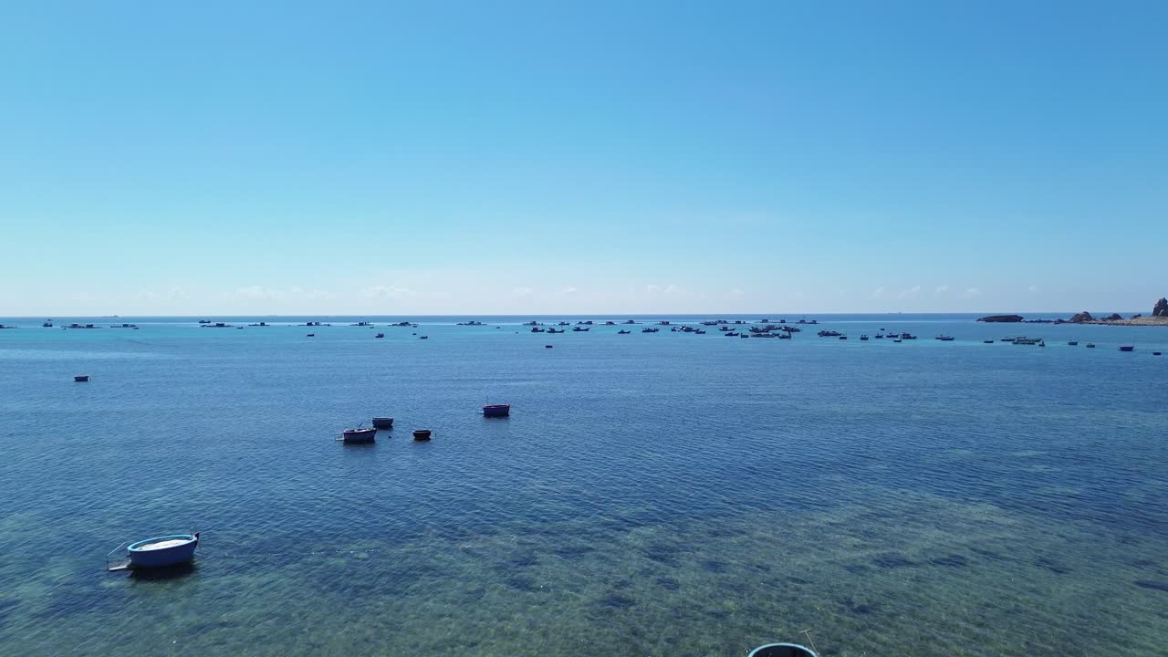 A slow forward aerial shot showing numerous traditional fishing boats anchored near the coast of Ninh Hải, Ninh Hải District, Ninh Thuận, Vietnam