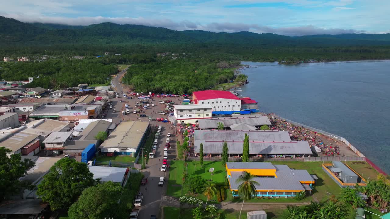 Morning Sundaun fish Market Wewak Hill buildings cars traffic people Boram road Wewak Papua New Guinea aerial drone downtown coastal town Sundaun Market Dogreto Bay sunny blue sky forward pan up