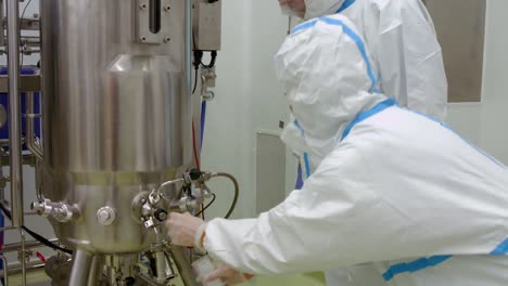 scientists in protective suits working on vat