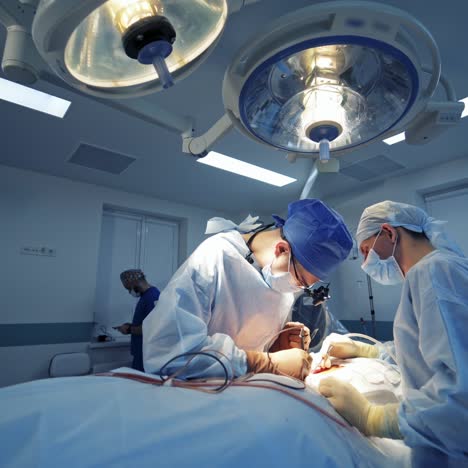 modern surgical room in the hospital. doctors perform neurosurgery to a patient under medical lamp. light spacious operating theater.