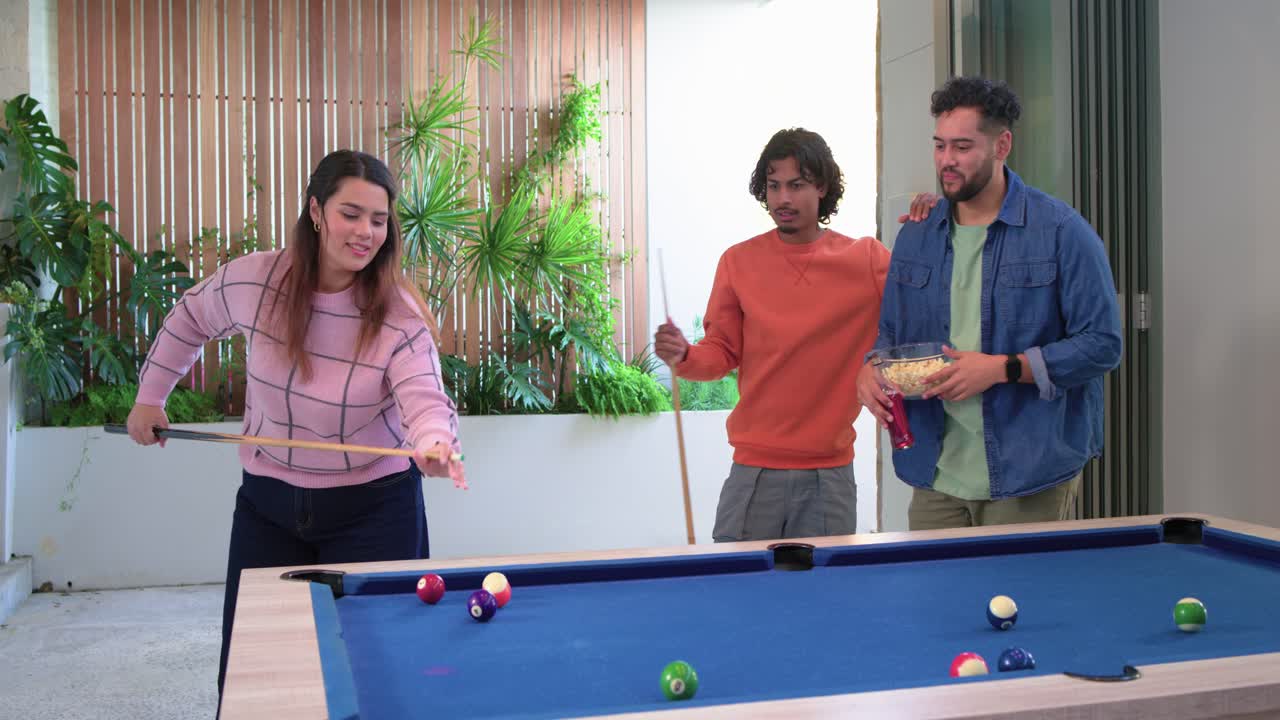 Diverse friends cheering, guiding woman arriving at patio pool table, bracing cue, breaking rack
