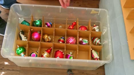 woman packing away the christmas decorations from the tree and boxing them up till next year