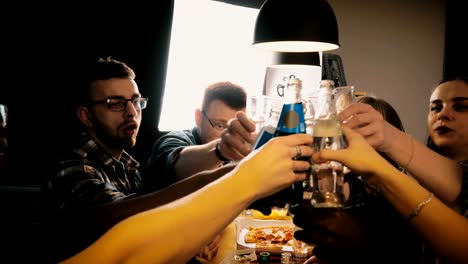 happy young multiethnic friends celebrating, eating pizza and having drinks at casual party by kitchen table slow motion