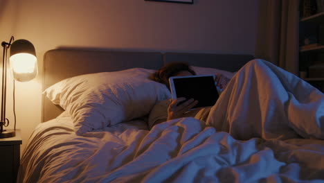 a person in bed using a tablet at night