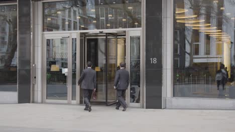 Los-Empresarios-Caminando-Hacia-El-Edificio-De-Oficinas-Con-Puerta-Giratoria-En-Mayfair,-Londres,-Gran-Bretaña.