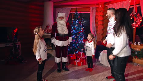 joyful family playing games with santa claus. santa gives tasks to parents and kids and they repeat after him. dancing moves with santa.