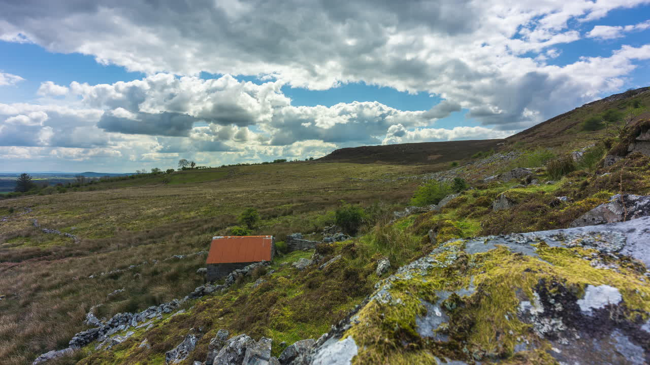 Scenic landscape with hills, clouds, and a small hut