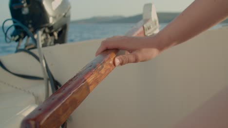 Closeup-of-female-hand-adjusting-course-moving-rudder-on-board-of-sailboat