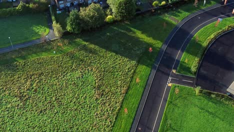 Aerial-view-above-road-leading-to-modern-housing-estate-property-rooftops-in-England-UK