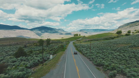 aerial of truck driving down a rural road through vast rolling hills