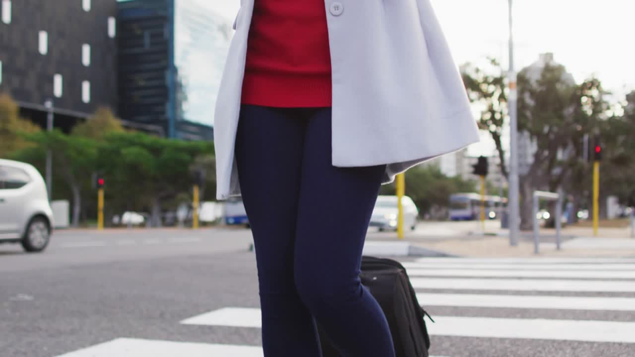 Woman commuting crossing pulling suitcase answering phone causing social media emojis filling face