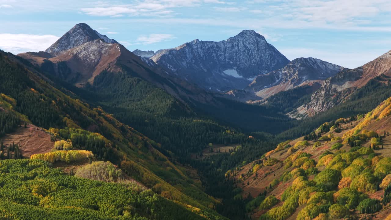 Poranek, słoneczne, błękitne niebo, ośnieżony szczyt 14er Capitol Peak, potok, szlak, pustynia, Aspen Snowmass, Kolorado, powietrzny dron, zielony zagajnik drzew osikowych, White River Forest, Elk Range, Góry Skaliste, ruch do przodu, panoramowanie w górę