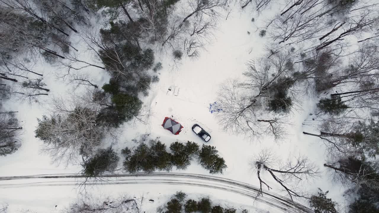 vista aérea descendente de arriba hacia abajo de la tienda de campaña y el camión blanco en el bosque de nieve