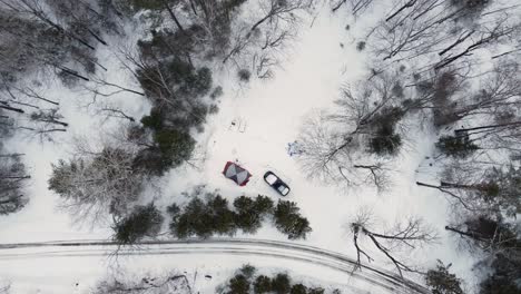 aerial descending top down view of camp tent and white truck in snow forest