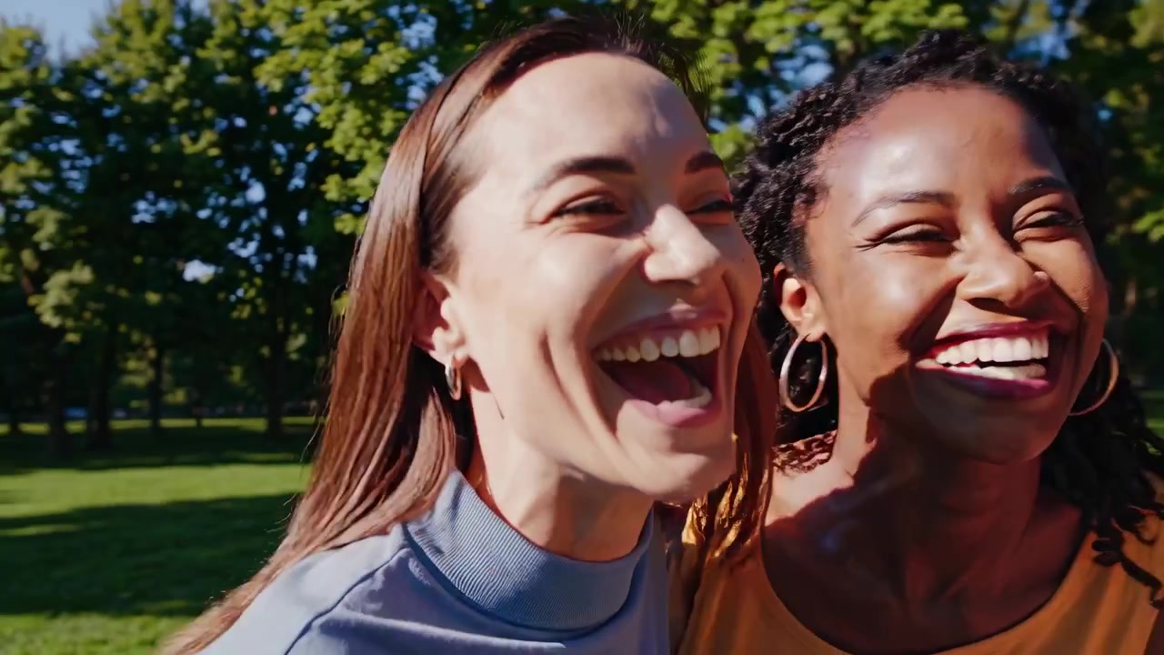 Happy Multi-Ethnic Women Friends Laughing Together in Sunny Park