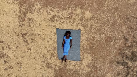 Aerial---A-girl-lying-down-in-the-park-enjoying-her-vacation,-rising-bird's-eye