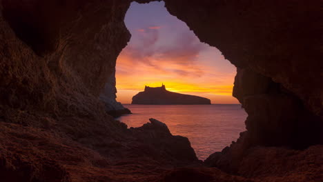 sunset over an island castle viewed from a cave entrance