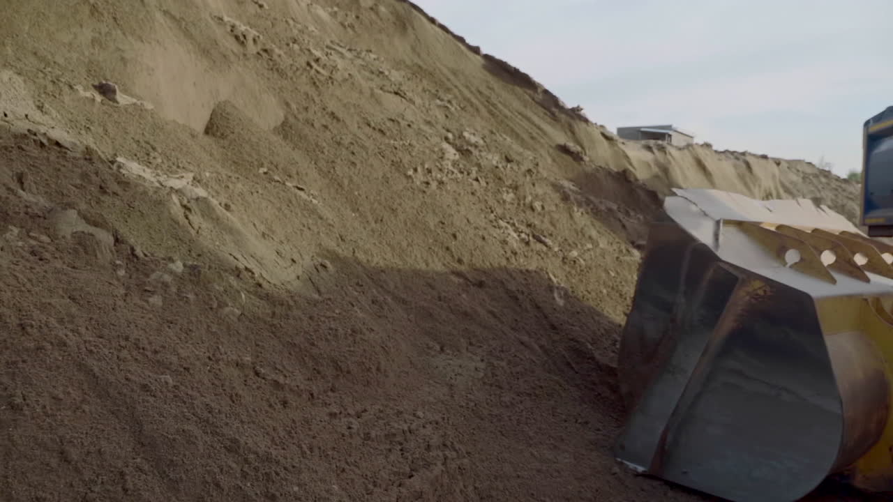 발굴기 가 경사 에서 모래 를 충전 하고 있다