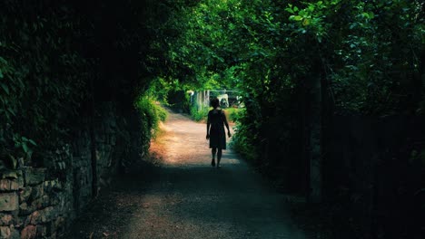 Back-view-of-young-caucasian-woman-walking-on-a-forest-archway-in-nature-wilderness