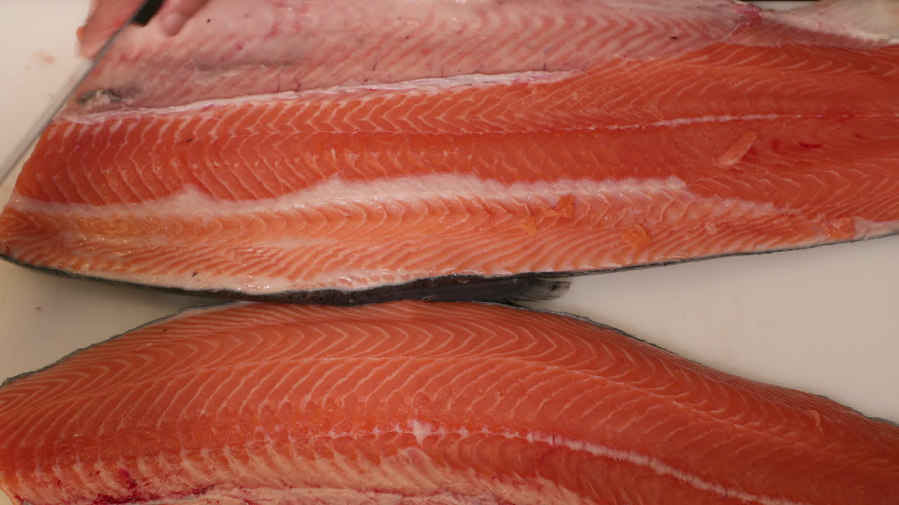 cuchillo raspando encima de la carne de salmón en una mesa blanca