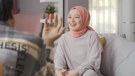 young muslim woman in hijab talking to her friend at home.