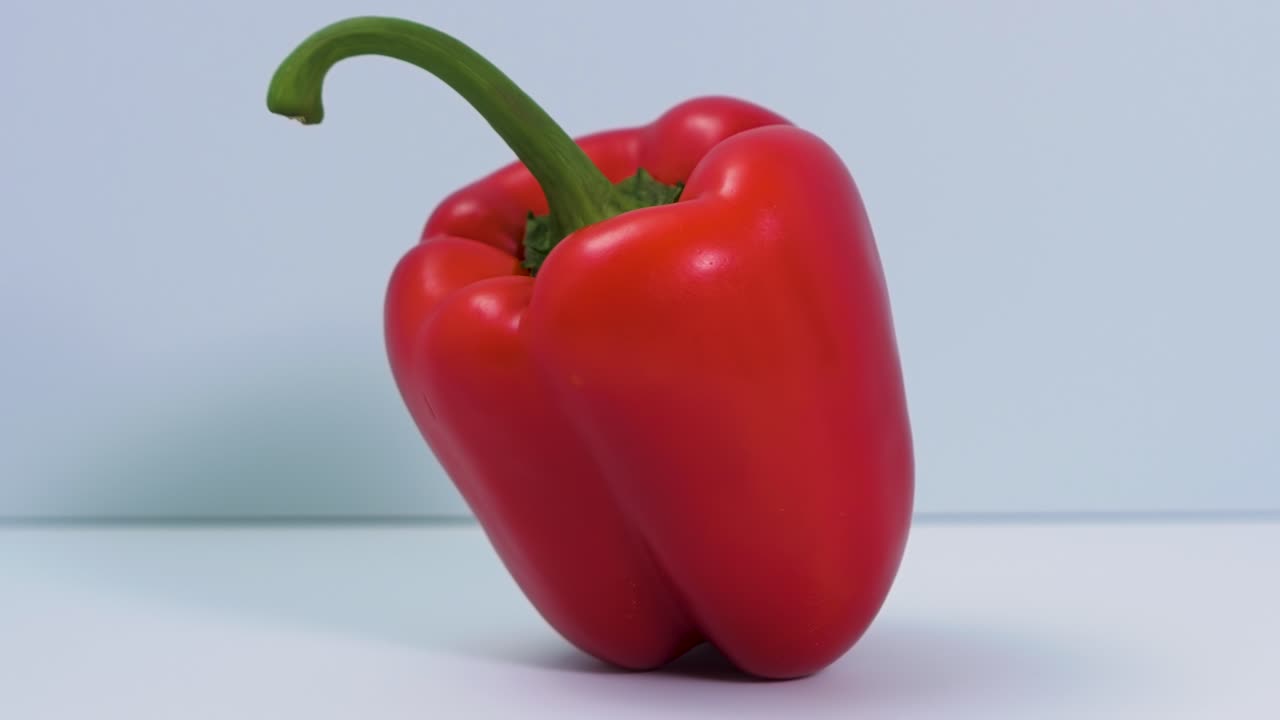 pimiento dulce rojo fresco gira sobre un fondo azul claro, comida saludable, concepto, cámara de primer plano gira a la izquierda