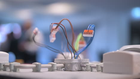 Electric-wires-in-different-colors-sticking-out-of-a-junction-box,-blurred-background,-focus-shift