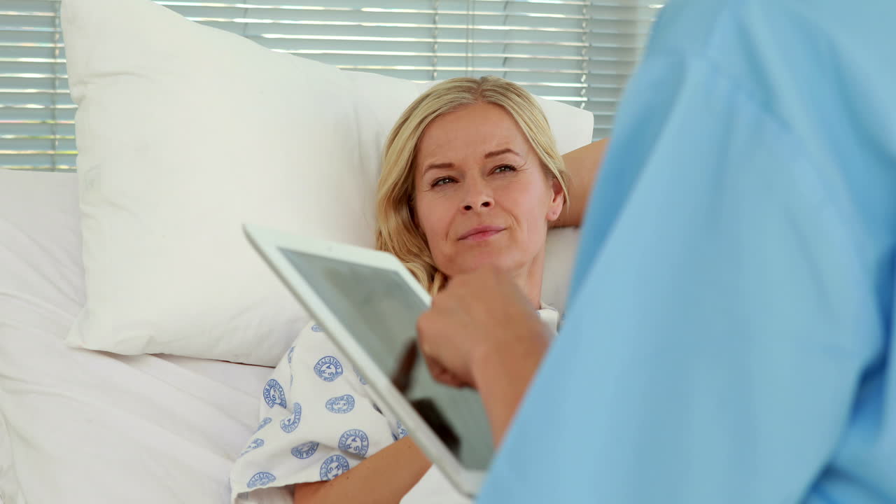 Doctor using tablet computer in front of patient bed 