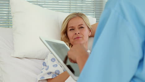 doctor using tablet computer in front of patient bed