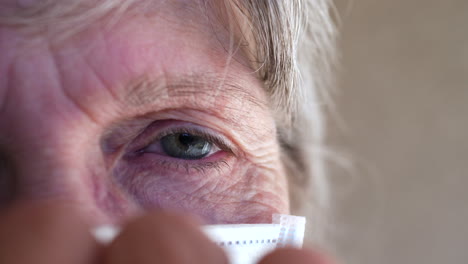 close up of an elderly wrinkled face putting on a medical patient mask to prevent spreading a contagious disease or getting sick