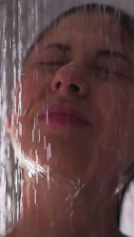 woman stands under pouring down water in shower closeup. dreaming lady with closed eyes washes body with spa procedures in bathroom. beauty care