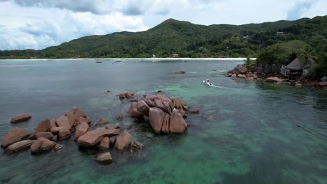 boat motoring through rock boulders along the coast of praslin island seychelles