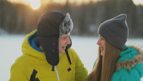 Ein-Mann-In-Einer-Gelben-Jacke-Und-Ein-Mädchen-In-Einem-Blauen-Overall-Fahren-In-Zeitlupe-Bei-Sonnenuntergang-Ski