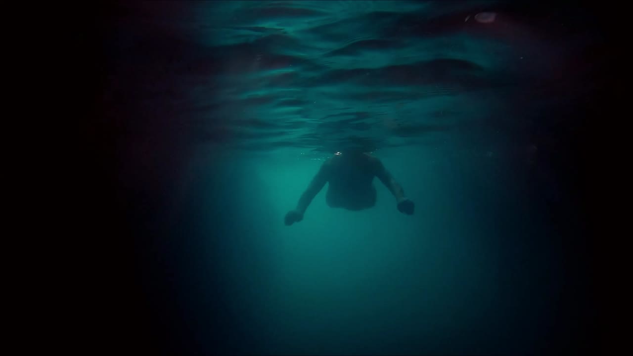 silueta de hombre buceando bajo el agua en una cueva en el mar