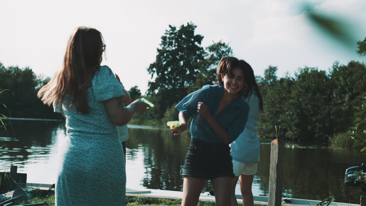Friends Enjoying a Water Gun Fight by the Lake