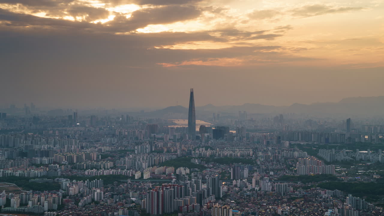 Stunning day to night time lapse of iconic view of Seoul, South Korea from Namhansanseong Mountain with Jamsil Tower prominently in the center. The sunset fades and the city skyline lights up.