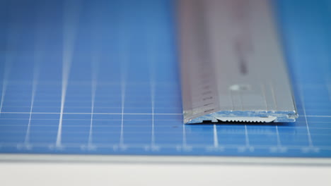 pencil draws line along ruler on blue archtect pad, close-up