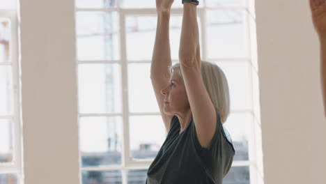 Yoga-Klasse-Schöne-Alte-Frau-Praktiziert-Krieger-Pose-Meditation-Und-Genießt-Das-Körperliche-Fitnesstraining-In-Der-Gruppe-Im-Studio