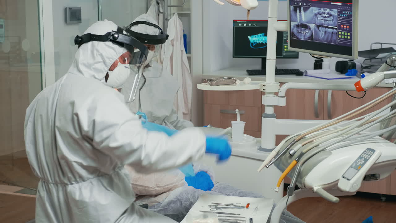 equipo de dentistas en ropa de abrigo tratando los dientes del paciente durante la covid-19