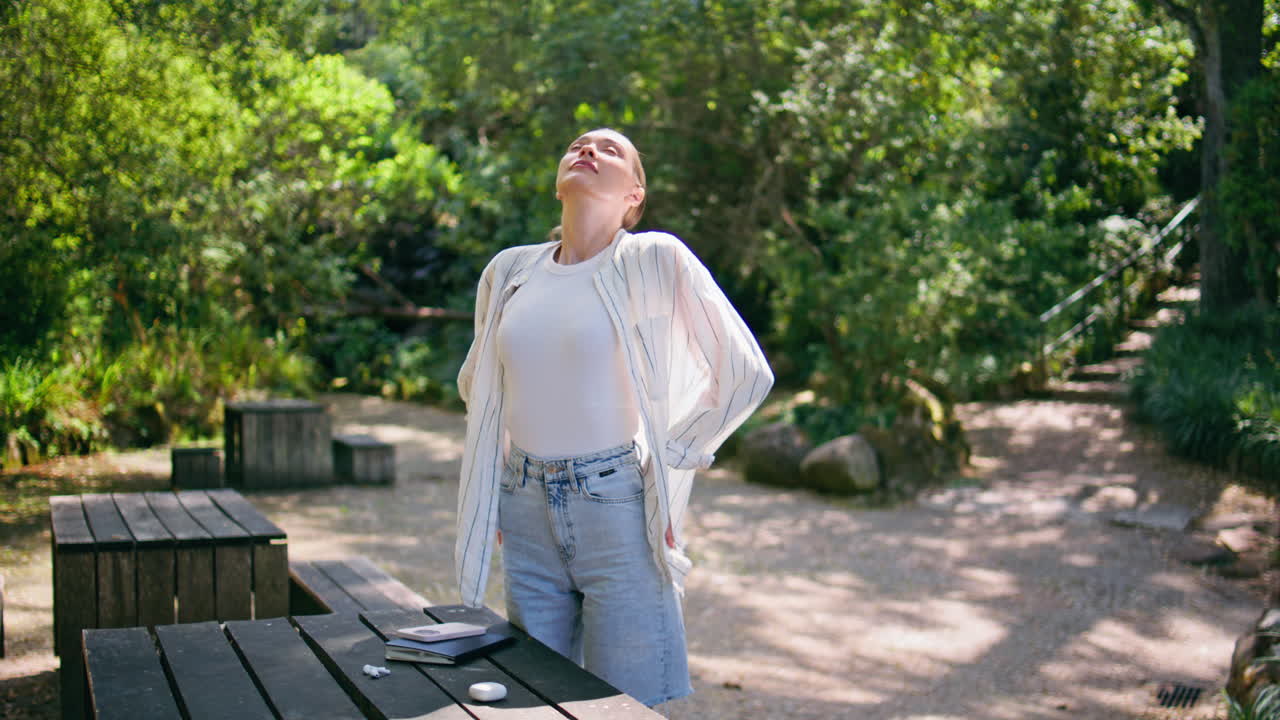 행복한 소녀는 자연을 즐기고 푸른 숲에서 신선한 공기를 흡수합니다. 여자는 휴식을 취하고 있습니다.