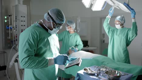 Portrait-of-diverse-surgeons-using-tablet-and-oxygen-mask-on-patient-in-slow-motion