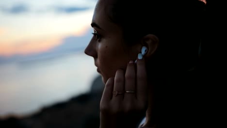 woman listening to music after exercising by the sea