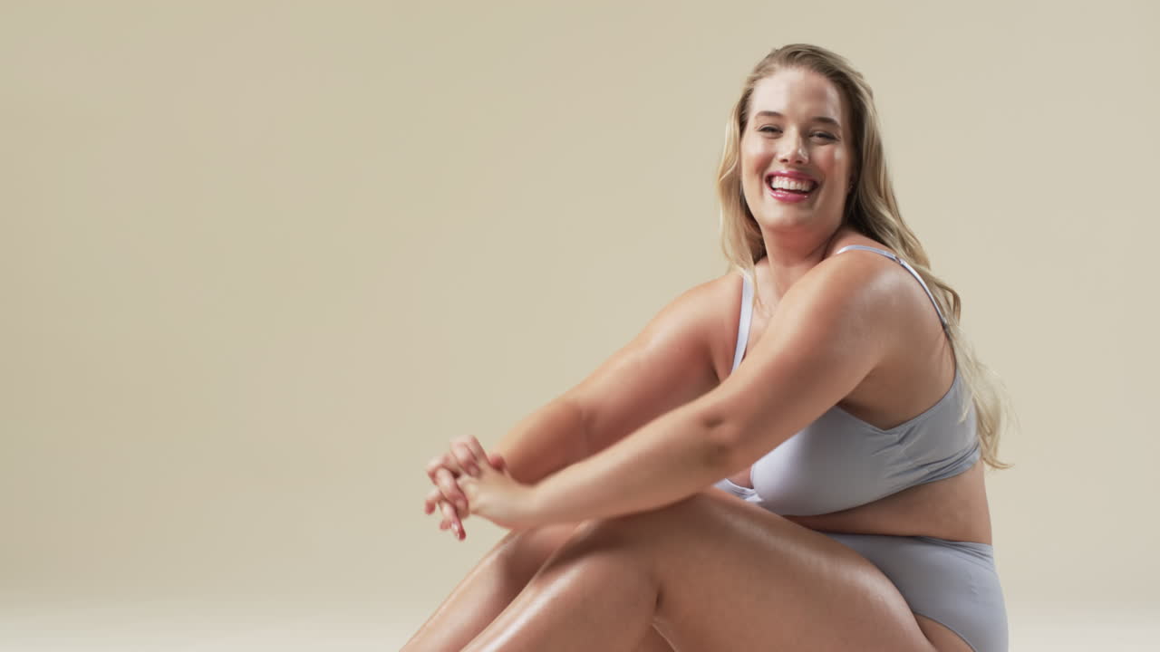 Caucasian plus size woman with long blonde hair and blue eyes sitting on floor, smiling, copy space