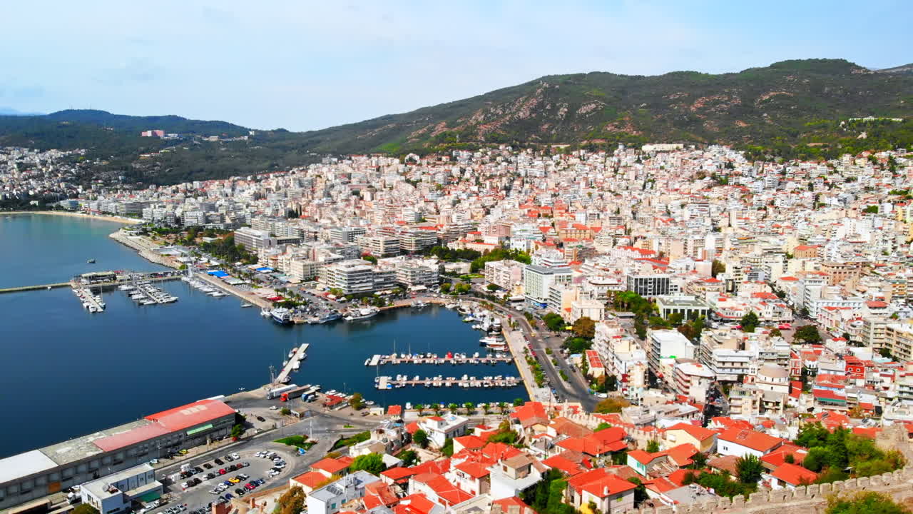 Aerial view of Kavala, a lot of buildings, Aegean sea coast, sea port, ancient fort, green hills in the distance, Greece