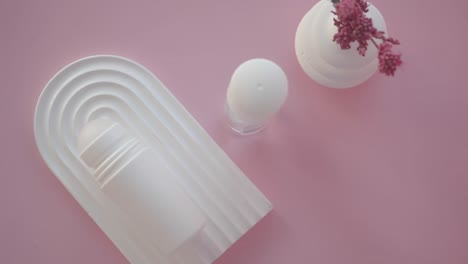 white deodorant bottle on arched tray with pink background