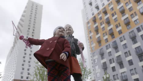 two girls playing outside modern apartment buildings