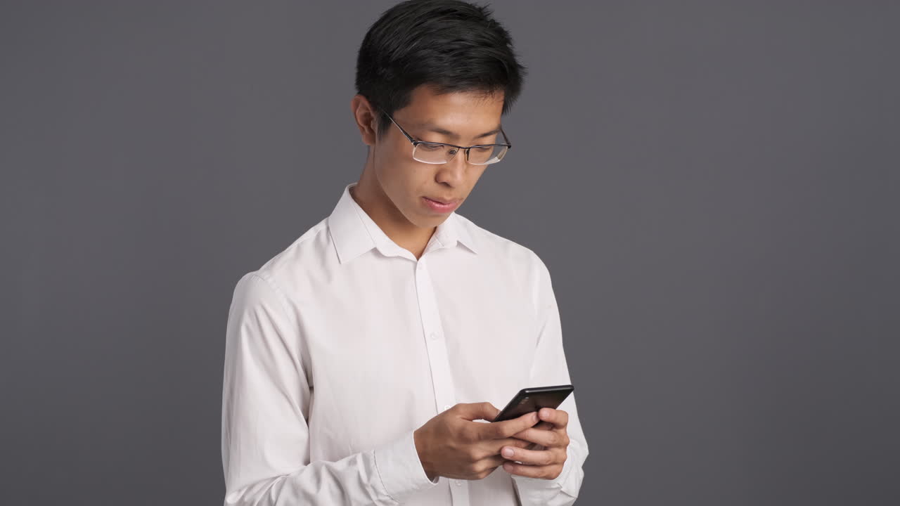 Uomo asiatico che usa lo smartphone e rimane sorpreso.