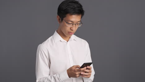 아시아 남자가 스마트폰을 사용하고 놀랐다.
